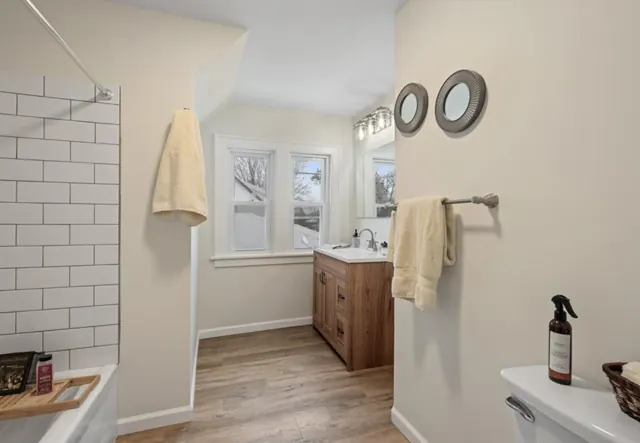 Bathroom with subway tile tub surround, wood vanity and wood-look flooring, St. Paul, MN
