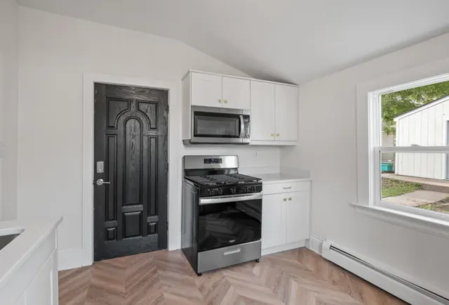 White shaker kitchen with gas range and herringbone flooring, St. Paul, MN